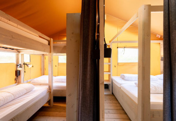 Innenaufnahme des Villatent Nomad Safarizeltes mit Etagenbetten und Doppelbetten in hellen Tönen.