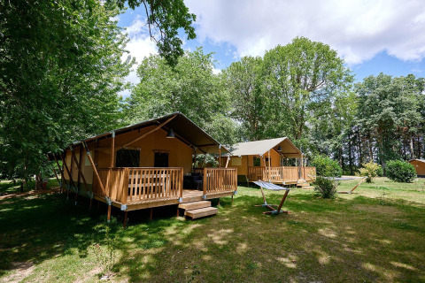 Villatent Nomad safaritenten op Camping Lestaubière in Frankrijk, omgeven door bomen en grasveld.