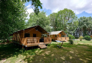 Tiendas safari Villatent Nomad en Camping Lestaubière, Francia, rodeadas de árboles y naturaleza verde.