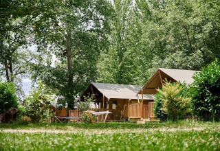 Tiendas safari en Villatent Nomad del Camping Lestaubière en Francia, rodeadas de frondosos árboles verdes.