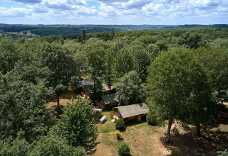 Vista aérea de la tienda safari Villatent Nomad en Camping Lestaubière, Francia, rodeada de frondosos árboles.