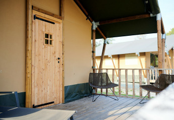 Véranda extérieure de la Safari Tent Wellness au Holiday Park Sallandshoeve, avec deux chaises et plancher bois.