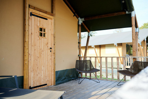 Udendørs terrasse af Safari Tent Wellness ved Holiday Park Sallandshoeve med to stole og trægulv.