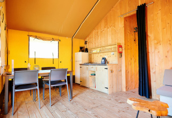 Binnenaanzicht van Safari Tent Wellness bij Holiday Park Sallandshoeve met eettafel en kitchenette.