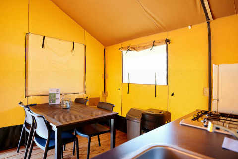 Interior de la Safari Tent Wellness en Holiday Park Sallandshoeve, Países Bajos, con mesa de comedor y cocina.