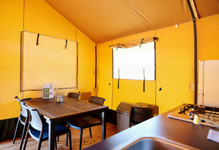 Interior de la Safari Tent Wellness en Holiday Park Sallandshoeve, Países Bajos, con mesa de comedor y cocina.