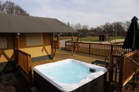 Tienda safari con jacuzzi en terraza de madera en el Holiday Park Sallandshoeve, Países Bajos.
