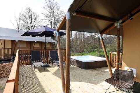Udendørs terrasse med spa, liggestole og parasol ved Safari Tent Wellness, Holiday Park Sallandshoeve, Holland.