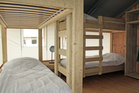 Vue intérieure d'une tente safari avec lits superposés et lit simple au Holiday Park Sallandshoeve, Pays-Bas.