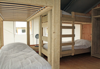 Vista interna di una tenda safari con letto a castello e singolo presso Holiday Park Sallandshoeve, Paesi Bassi.