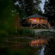 Verlichte safaritent op palen bij een vijver bij valavond in Holiday Park Sallandshoeve, Nederland.