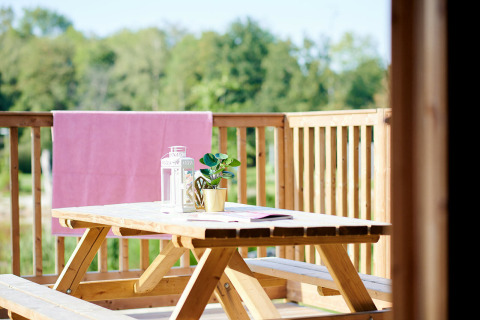 Mesa de picnic de madera con faroles y planta en la terraza de Safaricottage XL en Holiday Park Sallandshoeve.