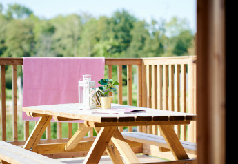 Houten picknicktafel met lantaarns en plant op het terras van Safaricottage XL, Holiday Park Sallandshoeve.