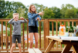 Dos niños juegan en una terraza de madera en la Safaricottage XL del Holiday Park Sallandshoeve, Países Bajos.
