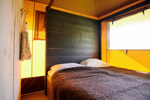 Dormitorio de tienda safari Safaricottage XL con cama doble en Holiday Park Sallandshoeve, Países Bajos.