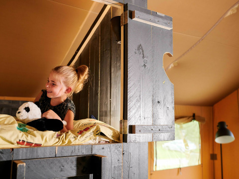 Meisje met pandaknuffel op een hoogslaper in Safaricottage XL in Vakantiepark Sallandshoeve, Nederland.