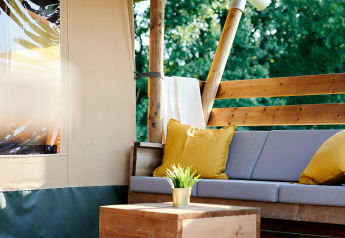 Coin salon extérieur sous tente Safaricottage XL avec coussins jaunes, au Holiday Park Sallandshoeve aux Pays-Bas.