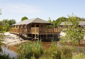 Grote Safaricottage XL met veranda aan het water bij Holiday Park Sallandshoeve in Nederland, omringd door natuur.