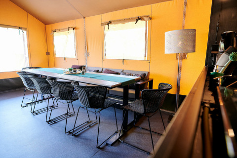 Innenaufnahme des Safaricottage XL im Holiday Park Sallandshoeve mit Esstisch und schwarzen Stühlen.