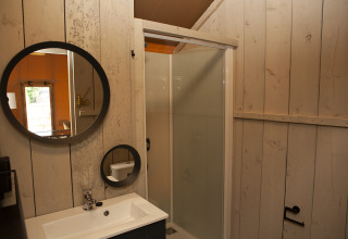 Badkamer in Safaricottage XL met douche, ronde spiegels en wastafel bij Holiday Park Sallandshoeve.