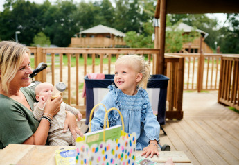 Famille profitant d’un moment sur la terrasse d’une Safaricottage XL au Holiday Park Sallandshoeve, Pays-Bas.