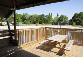 Terrasse en bois avec table de pique-nique au bord du lac à Safaricottage XL, Holiday Park Sallandshoeve, Pays-Bas.