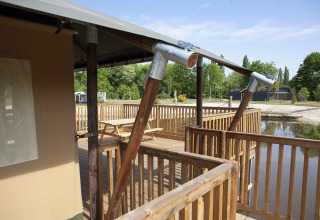Vue depuis la terrasse d’une tente safari avec rambarde en bois, au bord de l’eau au Holiday Park Sallandshoeve.