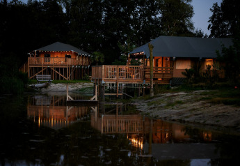 Tentes safari éclairées au bord du lac au Holiday Park Sallandshoeve aux Pays-Bas, photographiées le soir.