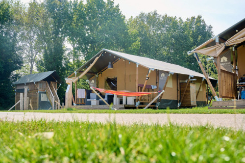 Tente safari au Holiday Park Sallandshoeve aux Pays-Bas, entourée de pelouse et d’arbres verdoyants.