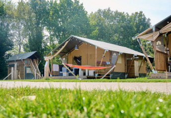 Tente safari au Holiday Park Sallandshoeve aux Pays-Bas, entourée de pelouse et d’arbres verdoyants.