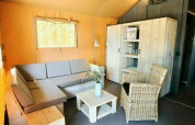 Espace salon d'une tente safari au Holiday Park Sallandshoeve, Pays-Bas, avec canapé et fauteuil en osier.