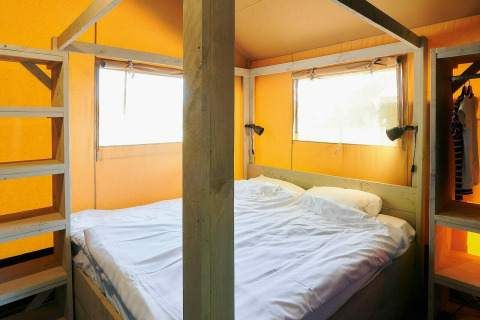 Vue intérieure d'une tente safari avec lit double et cadre en bois au Holiday Park Sallandshoeve aux Pays-Bas.