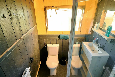 Salle de bain dans une tente safari au Holiday Park Sallandshoeve, Pays-Bas, avec deux toilettes et un lavabo.