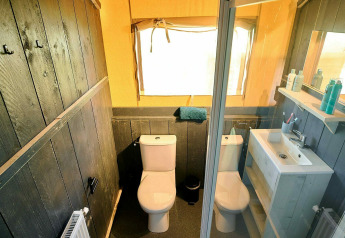 Salle de bain dans une tente safari au Holiday Park Sallandshoeve, Pays-Bas, avec deux toilettes et un lavabo.