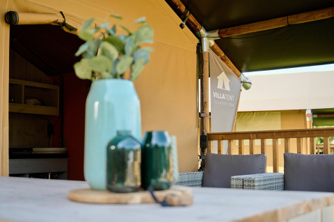 Table extérieure avec vases devant une tente safari au Holiday Park Sallandshoeve, Pays-Bas, ambiance détendue.