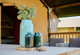 Table extérieure avec vases devant une tente safari au Holiday Park Sallandshoeve, Pays-Bas, ambiance détendue.