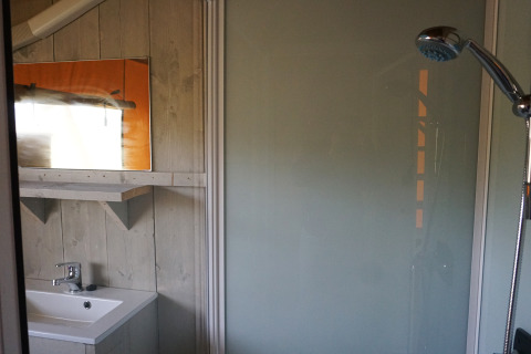 Salle de bain dans Safaritent avec douche, lavabo et miroir au Holiday Park Sallandshoeve, Pays-Bas.