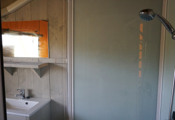 Badkamer in Safaritent met douche, wastafel en spiegel bij Holiday Park Sallandshoeve, Nederland.