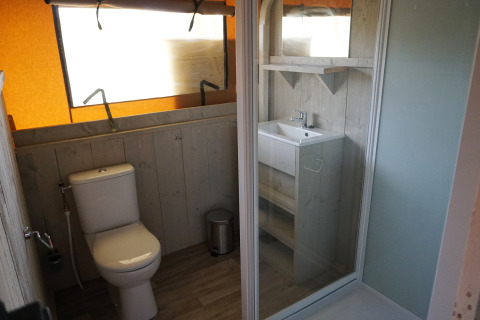 Bathroom inside a safari tent at Holiday Park Sallandshoeve in the Netherlands, featuring toilet and sink.