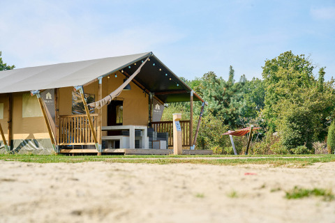 Safari-Zelt im Holiday Park Sallandshoeve, Niederlande, mit Terrasse und Hängematte in grüner Umgebung.