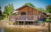 Niños juegan junto al agua frente a una tienda safari de lujo en Holiday Park Sallandshoeve, Países Bajos.