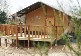 Luxe safaritent aan het water bij Holiday Park Sallandshoeve in Nederland, met houten terras en overkapping.