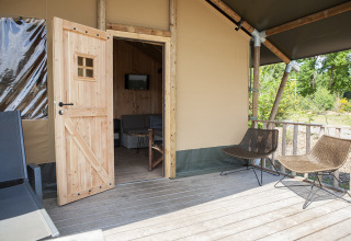 Vista sulla veranda e ingresso di una tenda safari di lusso al Holiday Park Sallandshoeve nei Paesi Bassi.