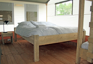 Intérieur d'une tente safari de luxe en bord de l'eau au Holiday Park Sallandshoeve aux Pays-Bas, avec plancher en bois.