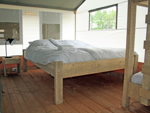 Innenraum eines Luxus-Safarizelts am Wasser im Holiday Park Sallandshoeve in den Niederlanden mit Holzboden.