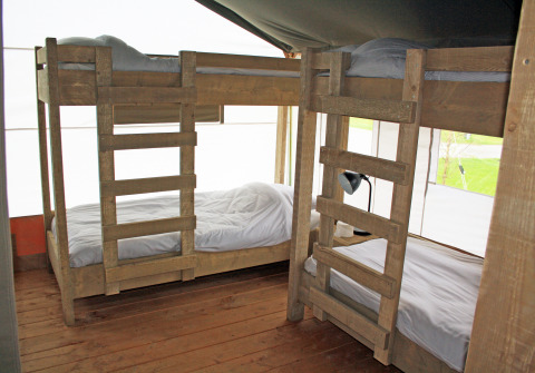 Interieur van een luxe safaritent op Holiday Park Sallandshoeve in Nederland met houten stapelbedden.