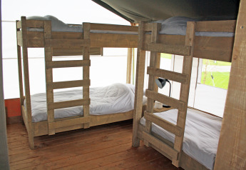 Interieur van een luxe safaritent op Holiday Park Sallandshoeve in Nederland met houten stapelbedden.