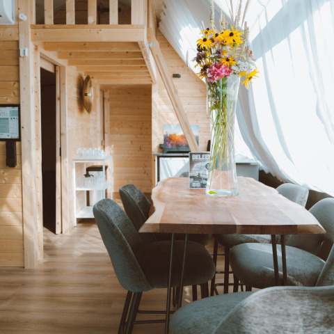 Interieur van de Big Oak Tent in Holiday Park Sallandshoeve in Nederland met houten meubels en bloemen.
