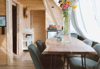 Interieur van de Big Oak Tent bij Holiday Park Sallandshoeve in Nederland met houten inrichting en bloemenvaas.