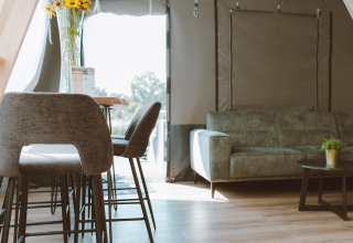 Interieur van de Big Oak Tent bij Holiday Park Sallandshoeve, Nederland, met bank en moderne eethoek.